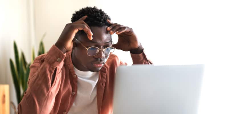 Person looking stressed at laptop after discovering identity theft