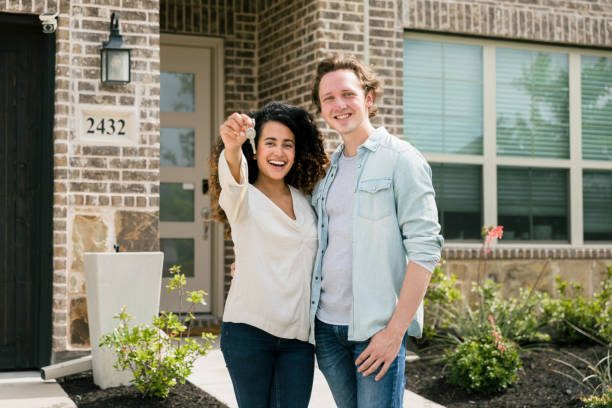 Couple holding house keys outside their new home